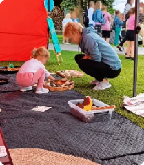 Maminka s holčičkou objevují přírodniny na trávě